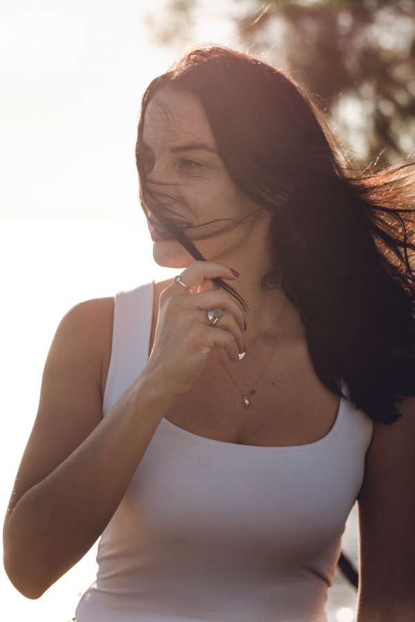 A girl with long hair, wearing a white blouse and a neckless